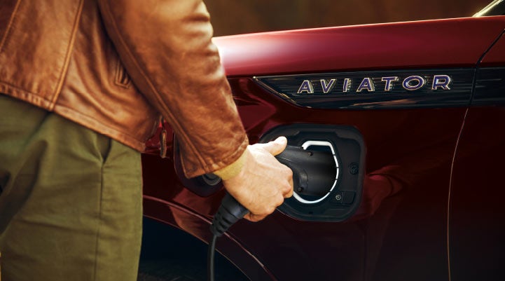 A hand is shown plugging in the charger into the charging port of a 2021 Lincoln Aviator | West Point Lincoln in Houston TX