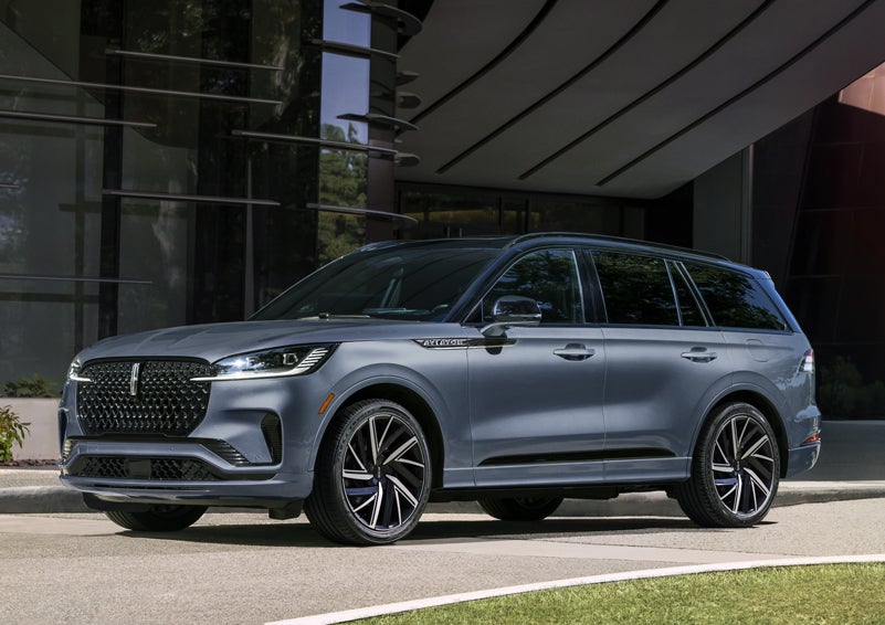 A gray 2025 Lincoln Aviator® SUV is parked outside a modern building showcasing the driver’s side of the vehicle. | West Point Lincoln in Houston TX