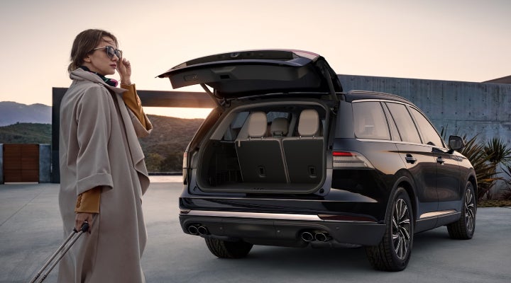 A woman approaches a 2026 Lincoln Aviator® SUV with its rear liftgate open. | West Point Lincoln in Houston TX
