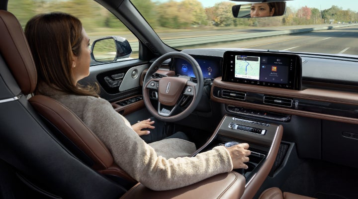 A 2026 Lincoln Aviator® SUV is being driven hands-free on a highway near a forest | West Point Lincoln in Houston TX