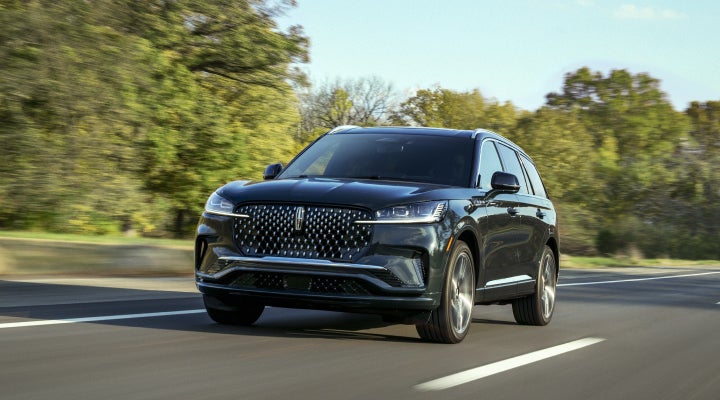 A 2026 Lincoln Black Label™ Aviator® SUV is being driven down a road lined with trees. | West Point Lincoln in Houston TX