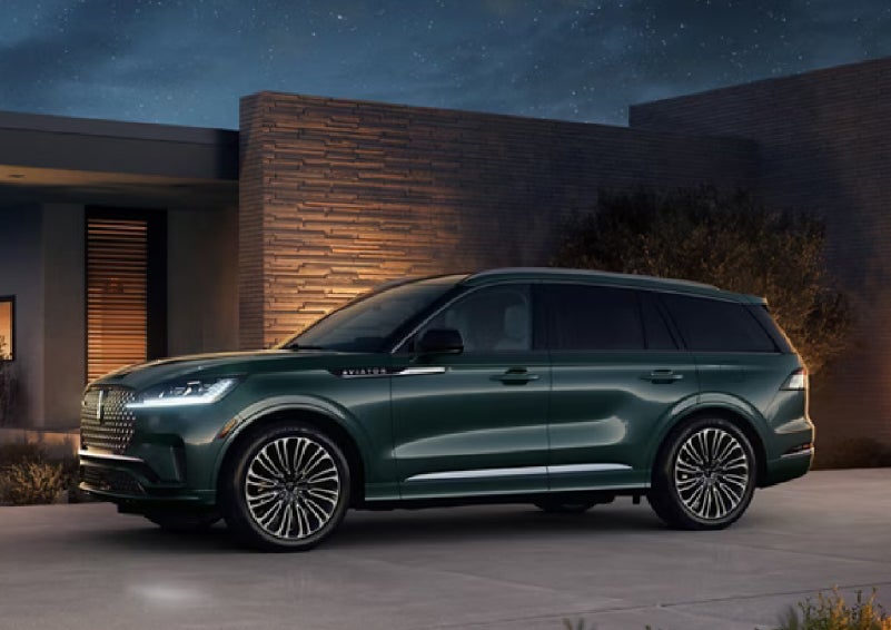 A green 2027 Lincoln Aviator® SUV is parked outside a contemporary home. | West Point Lincoln in Houston TX