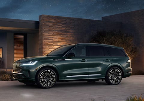 A green 2027 Lincoln Aviator® SUV is parked outside a contemporary home. | West Point Lincoln in Houston TX