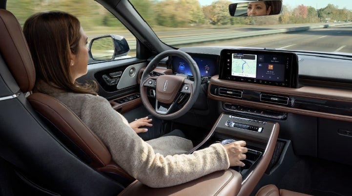 A 2027 Lincoln Aviator® SUV is being driven hands-free on a highway lined with trees. | West Point Lincoln in Houston TX
