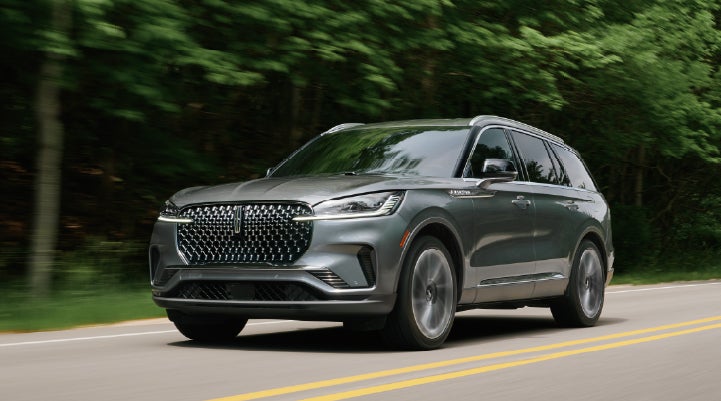 A 2027 Lincoln Aviator® SUV is being driven down a road lined with trees. | West Point Lincoln in Houston TX