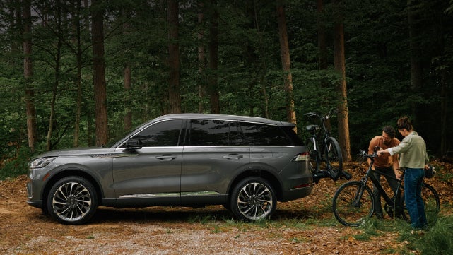 A father and son load e-bikes on a bike rack attached to a 2027 Lincoln Aviator® SUV. | West Point Lincoln in Houston TX