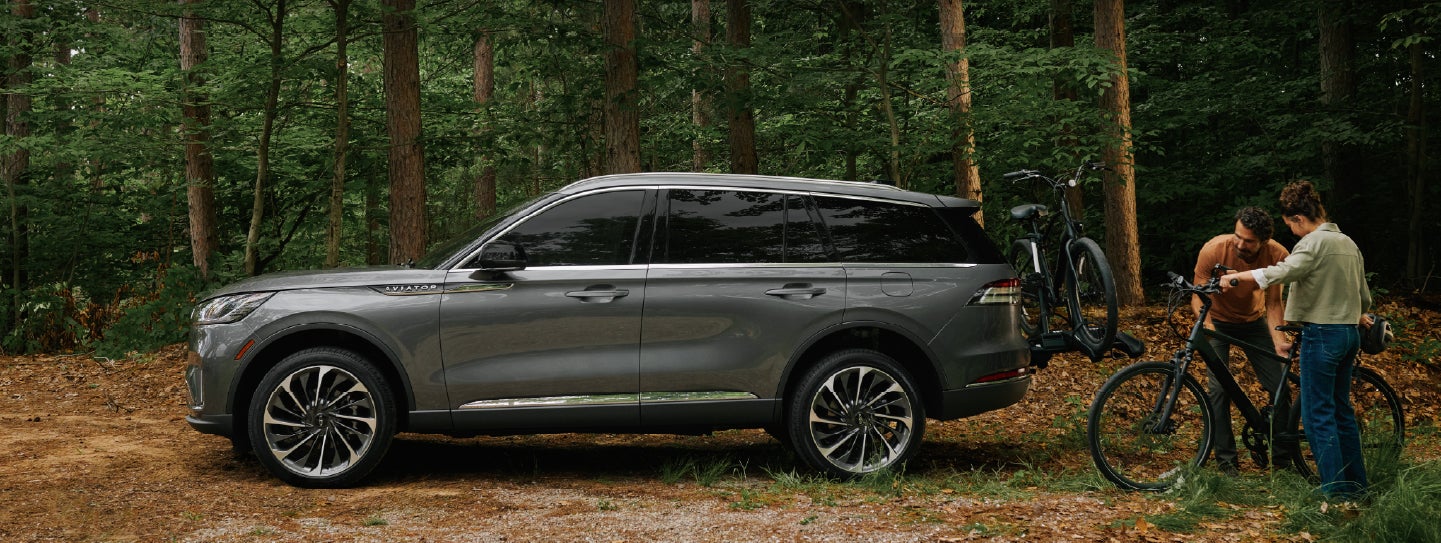 A father and son load e-bikes on a bike rack attached to a 2027 Lincoln Aviator® SUV. | West Point Lincoln in Houston TX